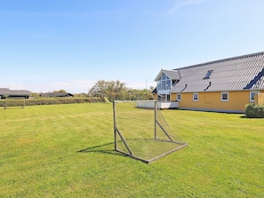 A residential area with a house, a fenced yard, and a playground in the background. - Spacious Holiday Home in Vinderup near Fjord (Vinderup)
