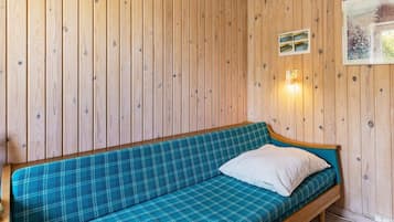 A wooden-paneled room with a blue plaid sofa and a white pillow.
