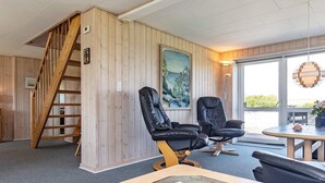 A room with a wooden interior, a black leather chair, a table with a magazine, and a painting on the wall. - Spacious Holiday Home in Vinderup near Fjord (Vinderup)