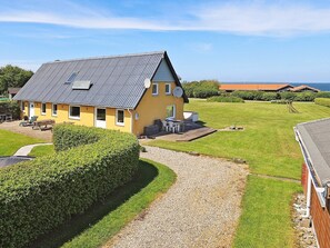A yellow house with a grey roof, a gravel driveway, and a well-maintained lawn. - Spacious Holiday Home in Vinderup near Fjord (Vinderup)
