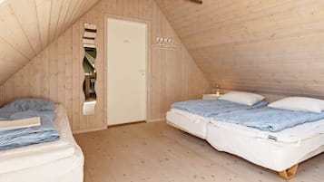 A room with two beds, a wooden ceiling, and a door with a mirror.