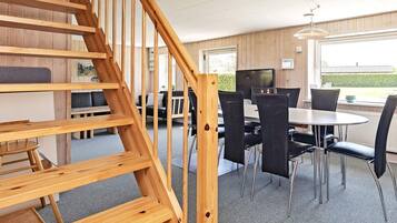 Una escalera de madera conduce a un comedor con una mesa y sillas.