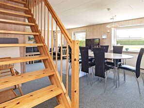 A wooden staircase leading to a dining area with a table and chairs. - Spacious Holiday Home in Vinderup near Fjord (Vinderup)