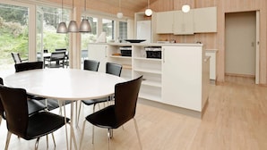 A modern kitchen with white cabinets, a central island, and pendant lighting. - 4 Star Holiday Home in Albaek (Aalbaek)