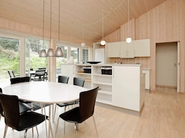 Una cocina moderna con armarios blancos, una isla central e iluminación colgante.