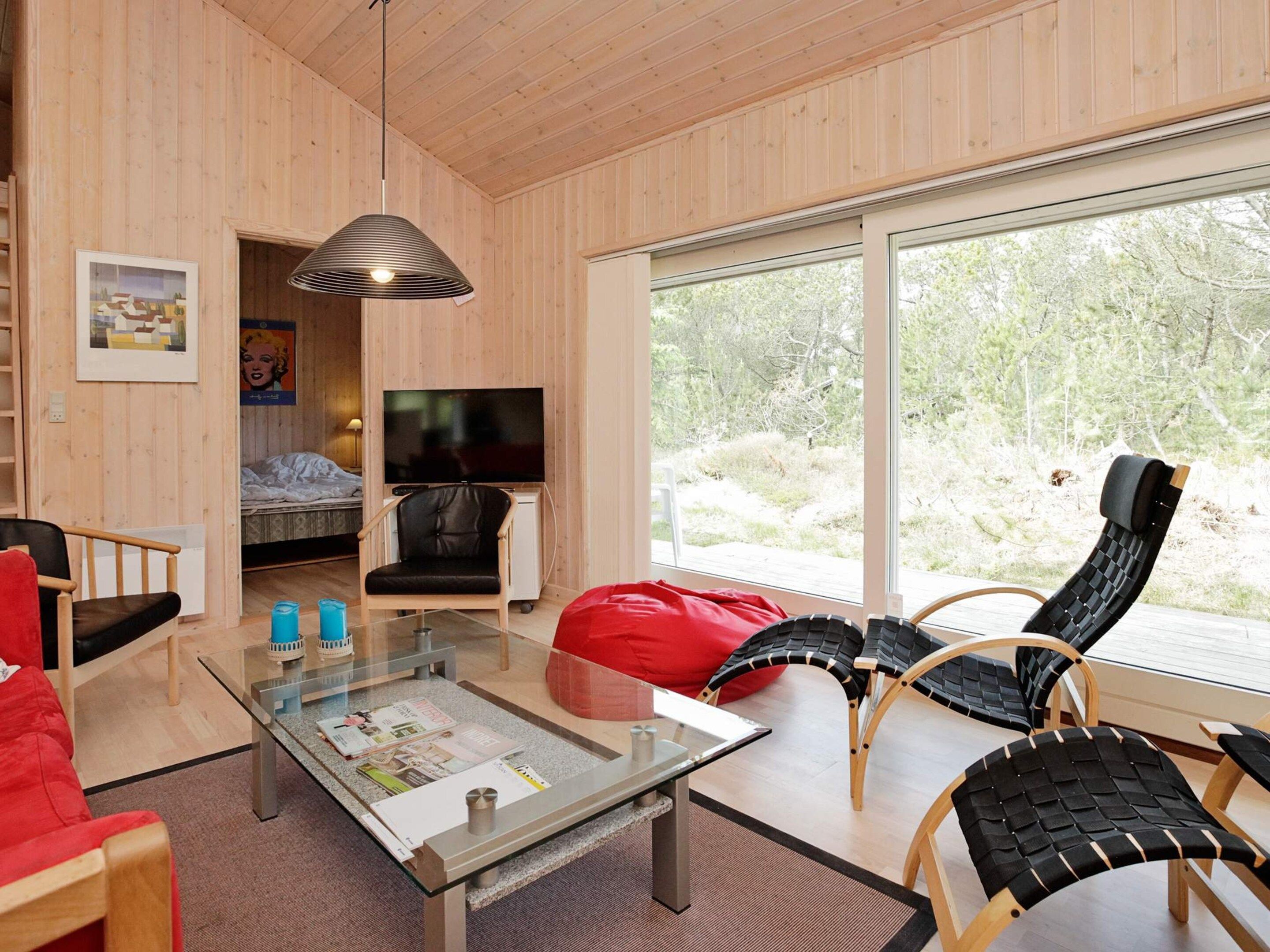 A modern living room with a glass coffee table, a red bean bag, and a television in a corner.