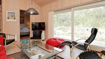 A modern living room with a glass coffee table, a red bean bag, and a television in a corner.