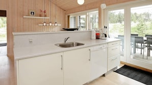 A modern kitchen with wooden walls, a stainless steel sink, white cabinets, and pendant lighting. - 4 Star Holiday Home in Albaek (Aalbaek)