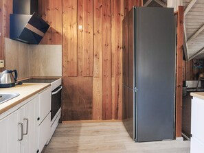Une cuisine avec des murs en bois, un réfrigérateur en acier inoxydable, une bouilloire et une cuisinière.
