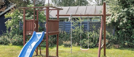 A playground with a slide, swings, and a wooden climbing structure.