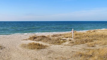 A beach with a lifeguard sign, sandy terrain, and the ocean.