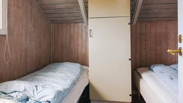 Ein kleines, gemütliches Zimmer mit zwei Einzelbetten, einer Holzbalkendecke und einem weißen Kleiderschrank.
