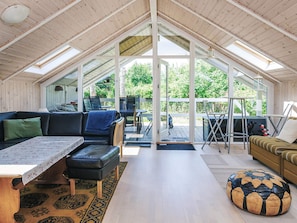 A spacious loft-style room with a high ceiling, large windows, and a view of greenery outside. - 5 Star Holiday Home in Dannemare (Dannemare)