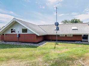 A single-story building with a sloped roof, a small attached garage, and a satellite dish. - 5 Star Holiday Home in Dannemare (Dannemare)