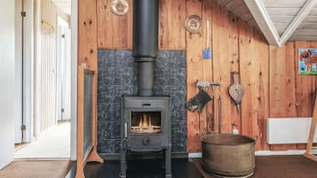 A wood-burning stove in a room with wooden walls and a tiled floor.