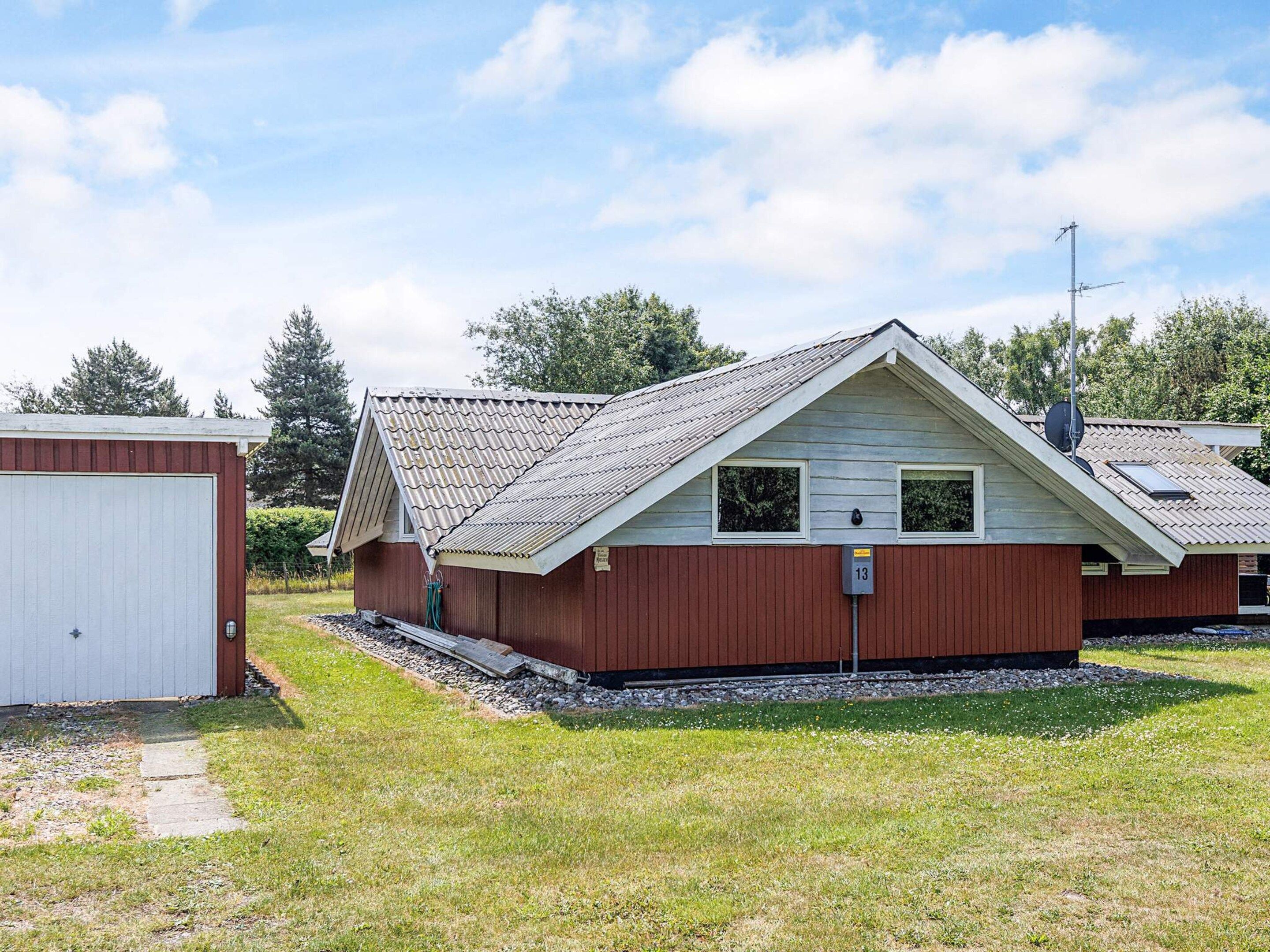 Ein eingeschossiges Gebäude mit Satteldach, einer kleinen Veranda und einer angebauten Garage links.