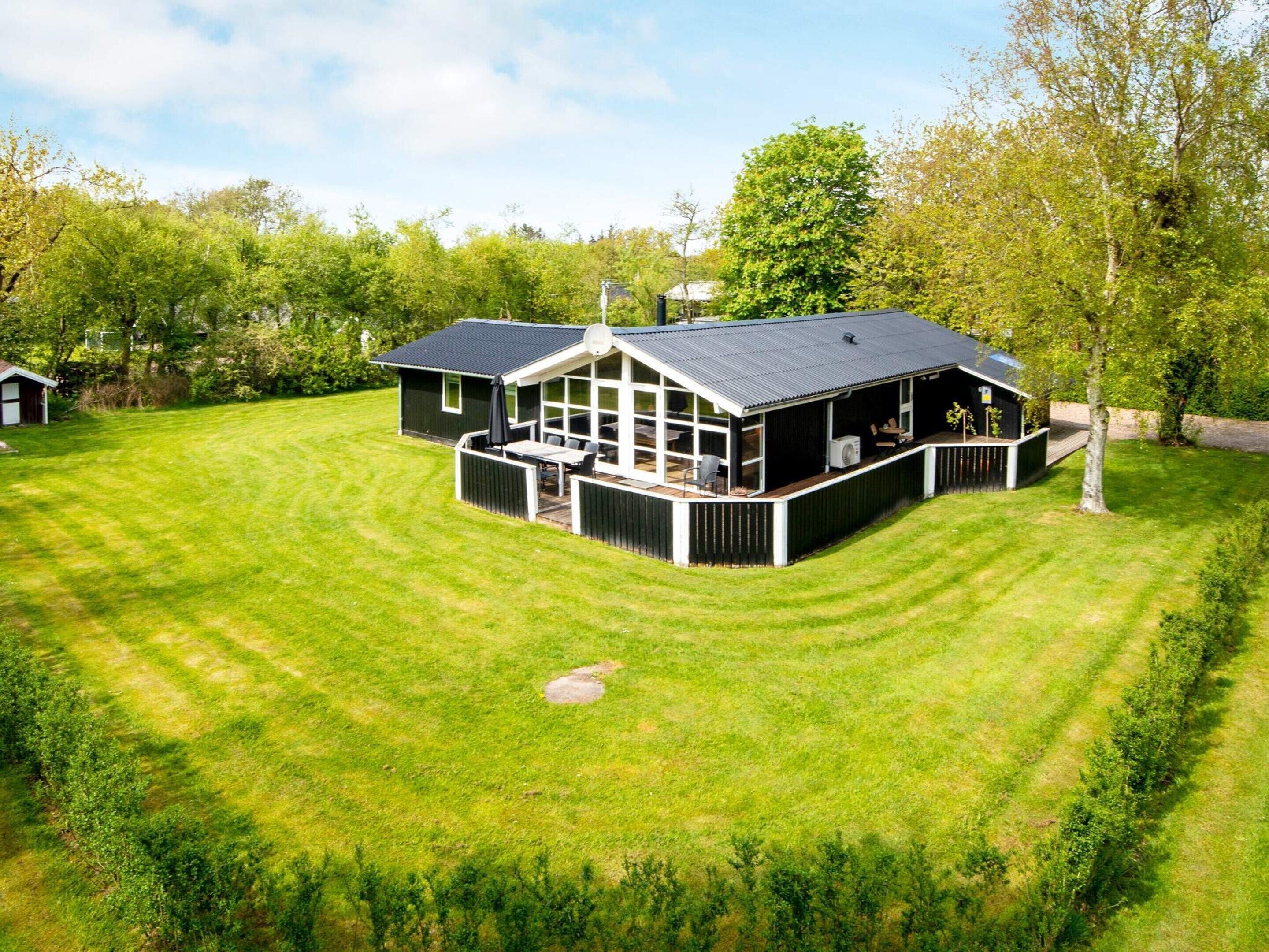 A modern house with a large deck, surrounded by a well-maintained lawn.