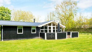 En svart metallbyggnad med ett stort fönster och en inglasad uteplats.