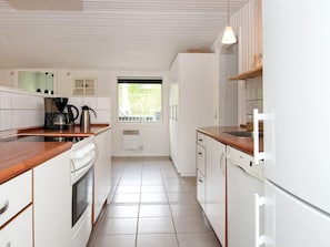 A modern kitchen with white cabinetry, a coffee maker, a kettle, and a window providing natural light. - 8 Person Holiday Home in Hemmet (Hemmet)