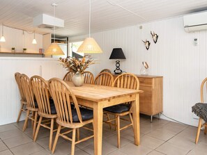 A dining area with a wooden table and chairs, a vase with dried flowers, pendant lights, a black lamp, and wall-mounted decor. - 8 Person Holiday Home in Hemmet (Hemmet)