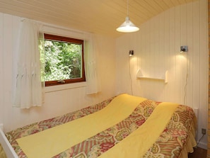 Ein Zimmer mit einem Bett, einem Vorhangfenster, einer Hängelampe und einem Wandregal.