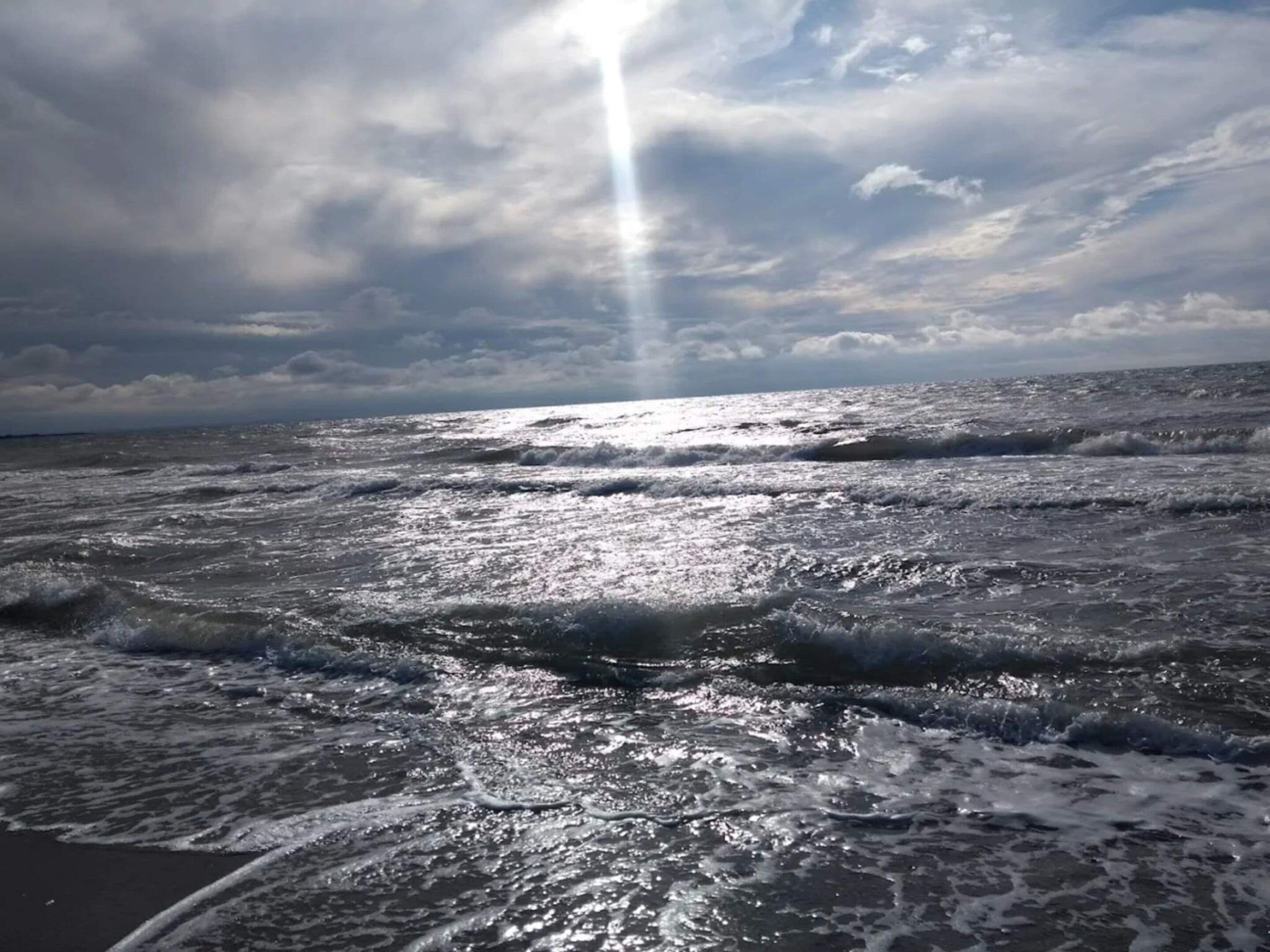 A beach with waves and a cloudy sky.