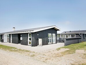 A modern building with a flat roof, large windows, and a visible chimney.