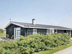 A modern single-story building with a dark exterior, large windows, and a visible chimney.