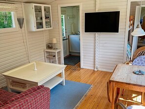 A room with a television, a cabinet with dishes, a small table, and a red plaid sofa. - Ideal Holiday Home in Stege near Sea (Stege)