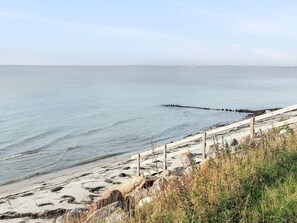 A coastal beach with a wooden fence and rocky terrain. - Ideal Holiday Home in Stege near Sea (Stege)
