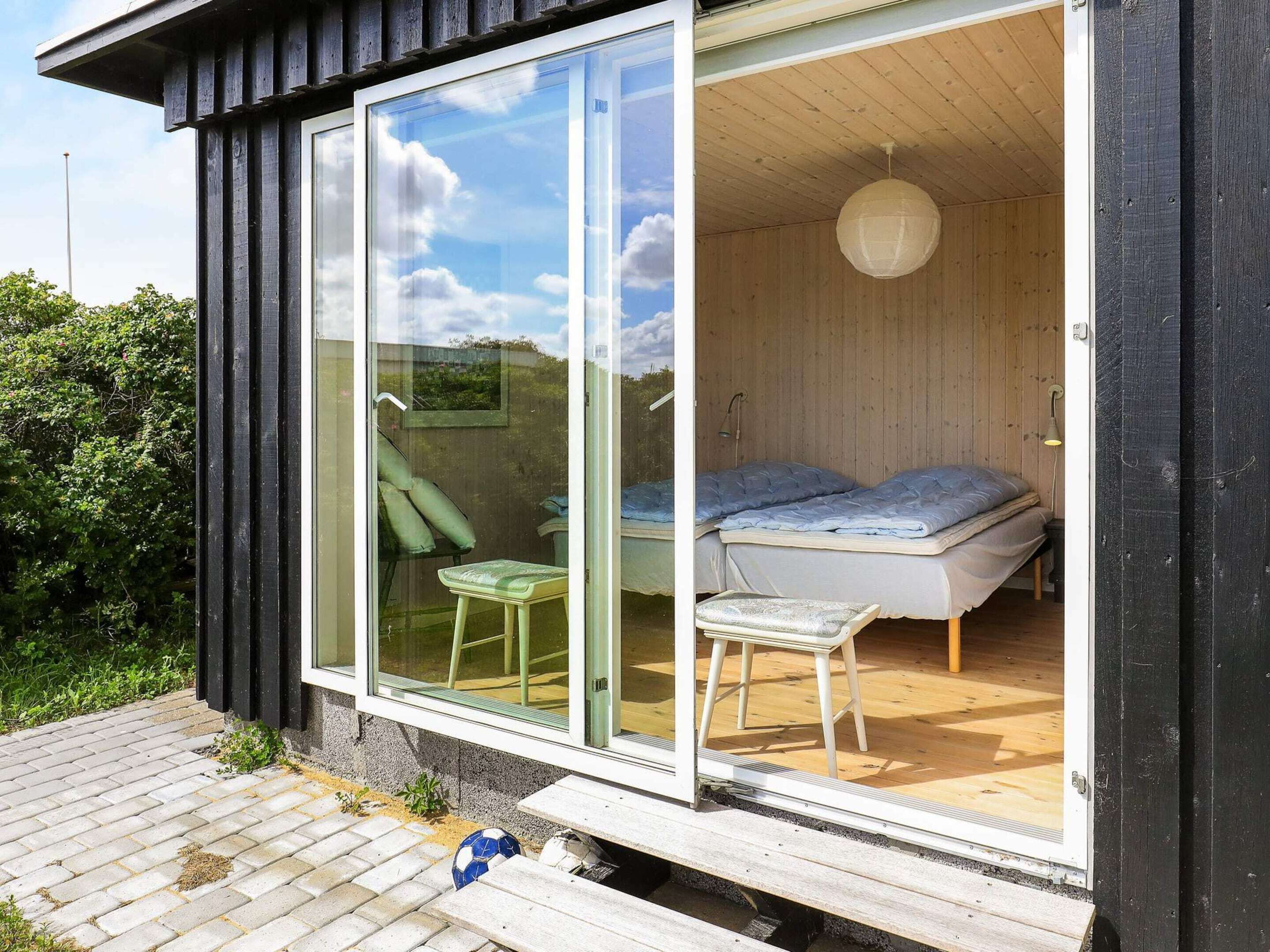 A modern cabin with a sliding glass door leading to a bedroom with two beds and a small table.