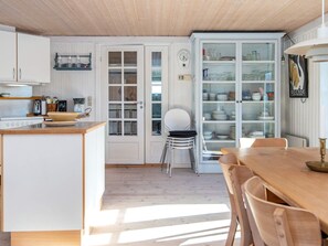 A kitchen with a wooden countertop, a dining table, and a cabinet with glass doors. - 4 Star Holiday Home in Ringkobing (Ringkobing)