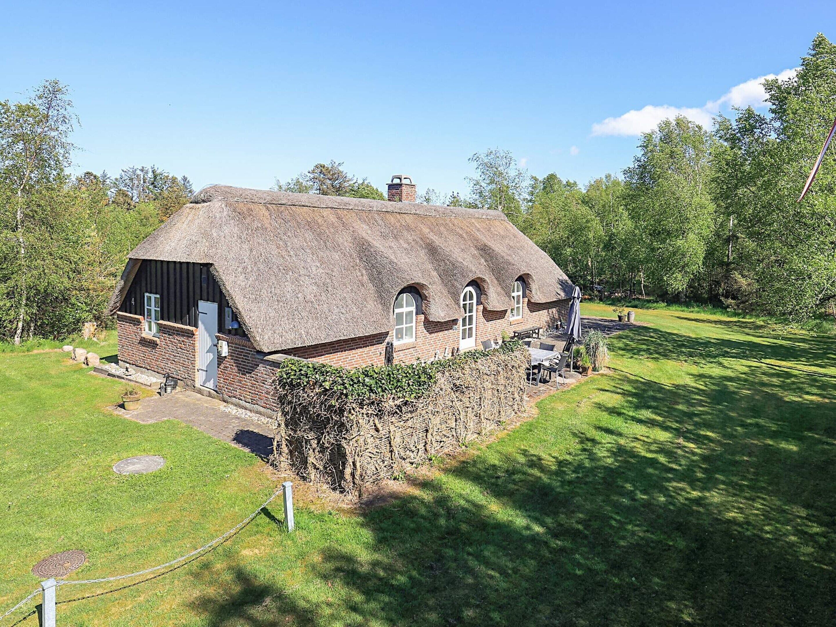 Un petit chalet au toit de chaume, aux murs en briques, doté d’un petit jardin et surplombant un ciel dégagé.