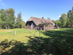 A traditional thatched-roof house with a fenced yard and a metal sculpture in the foreground. - Unique Pet Friendly Holiday Home in Jerup near Sea (Jerup)