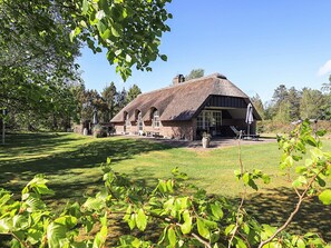 A thatched-roof building with a brick exterior, surrounded by a well-maintained lawn and trees. - Unique Pet Friendly Holiday Home in Jerup near Sea (Jerup)