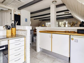 A kitchen with white cabinetry, a granite countertop, and a wooden backsplash. - Unique Pet Friendly Holiday Home in Jerup near Sea (Jerup)