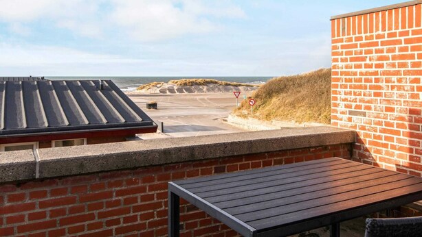A rooftop terrace with a view of the beach, a brick wall, and a wooden table. - Beachfront Bungalow Bliss - By Traum Ferienwohnungen (Henne)