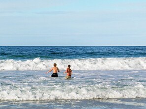 Two individuals in the ocean, with waves approaching the shore. - Holiday Home in Laukvik (Hadsel)