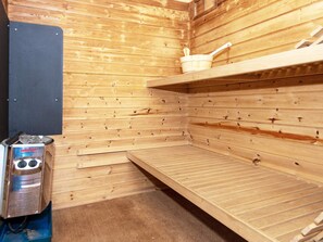 A sauna with wooden walls, a bench, a bucket, and a heater. - 5 Star Holiday Home in Ringkobing (Ringkobing)