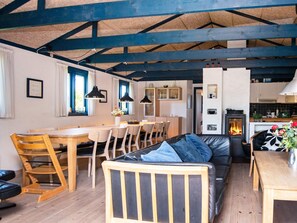 A cozy interior with a wooden dining table, chairs, a sofa, and a fireplace. - 5 Star Holiday Home in Ringkobing (Ringkobing)