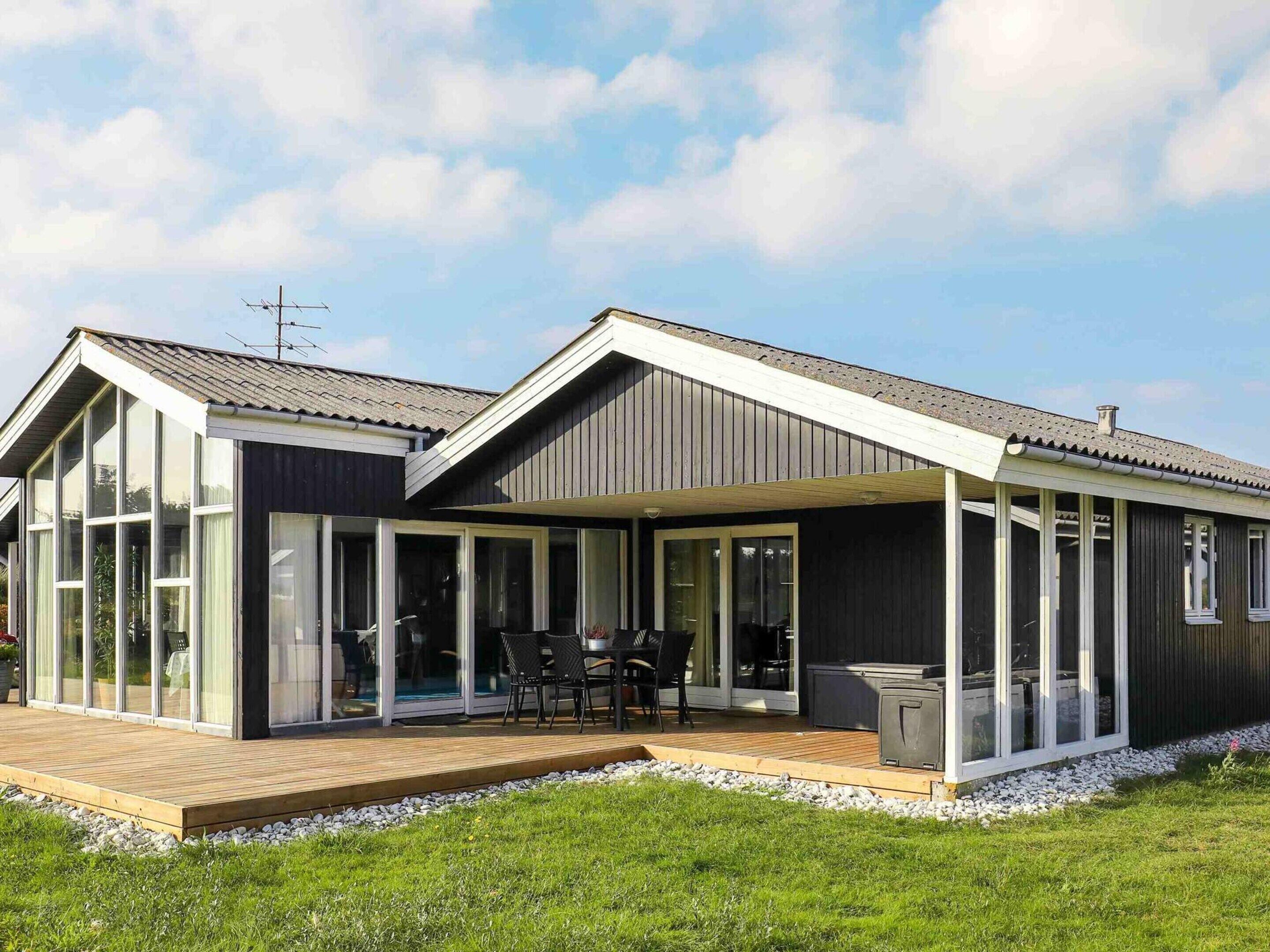 A modern house with a deck, large windows, and a covered outdoor area.