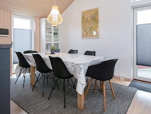 A dining area with a table set for six, surrounded by black chairs with wooden legs. - 4 Star Holiday Home in Vaeggerlose (Vaeggerlose)