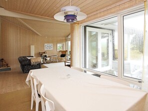 Um quarto com uma mesa grande, duas poltronas de balanço e uma janela com vista para o exterior.