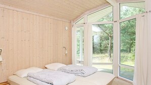 A room with a wooden ceiling, a bed with white bedding, a bedside table, and a window with curtains. - 4 Star Holiday Home in Jerup (Jerup)