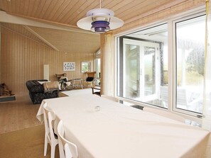 A room with a large table, chairs, a hanging light fixture, and a view through a large window. - 4 Star Holiday Home in Jerup (Jerup)