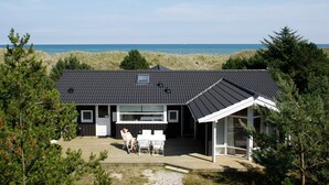 Ein modernes Haus mit Flachdach, großen Fenstern und einer Terrassenfläche.