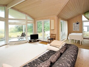 A spacious room with a large bed, a television, and a dining area with a table and chairs.