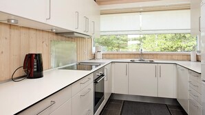 A modern kitchen with white cabinets, a built-in oven, and a coffee maker. - 4 Star Holiday Home in Jerup (Jerup)