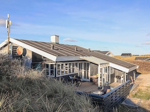 Een modern huis met een ruim terras, een schotelantenne en een helder uitzicht op het omliggende landschap.