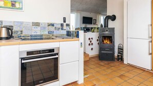 Moderni keittiö, jossa on sisäänrakennettu liesi, astianpesukone ja jääkaappi.